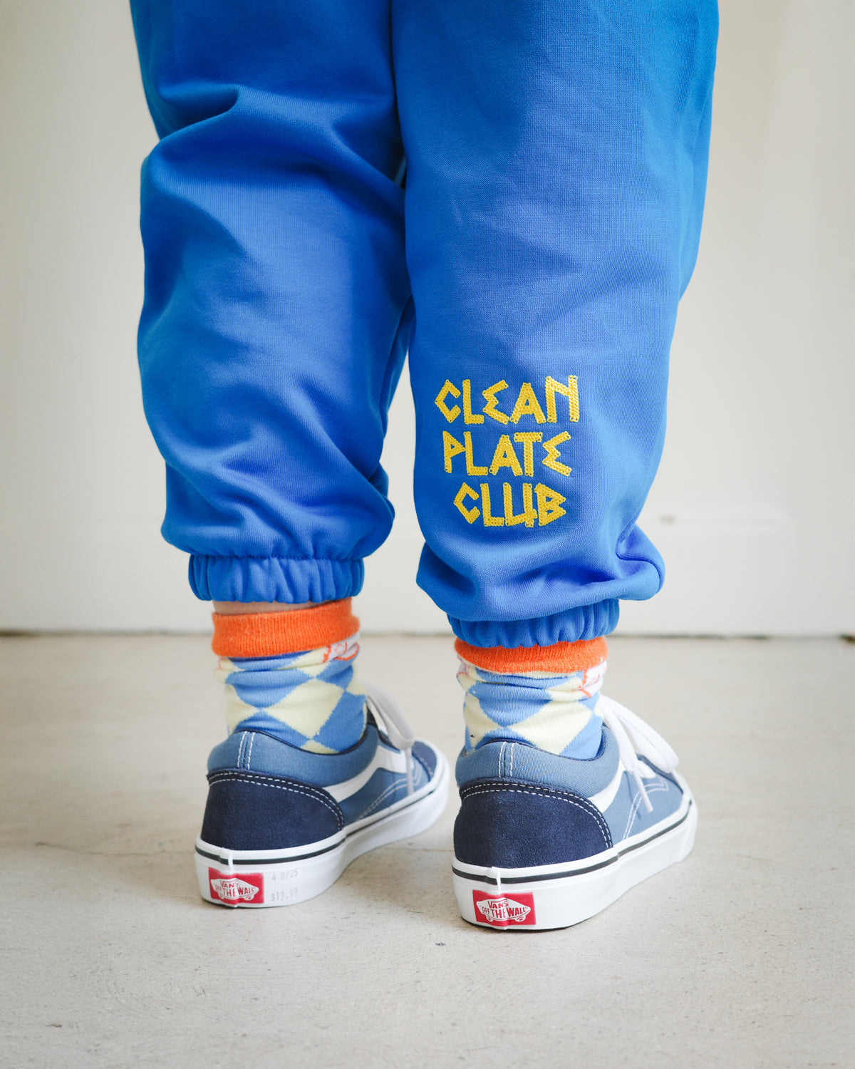 Close-up of chain embroidery on kids blue sweatpants, featuring Clean Plate Club text detail.