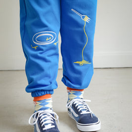 Close-up of chain embroidery on kids blue sweatpants, featuring playful food motifs: clean plate, spaghetti fork detail.