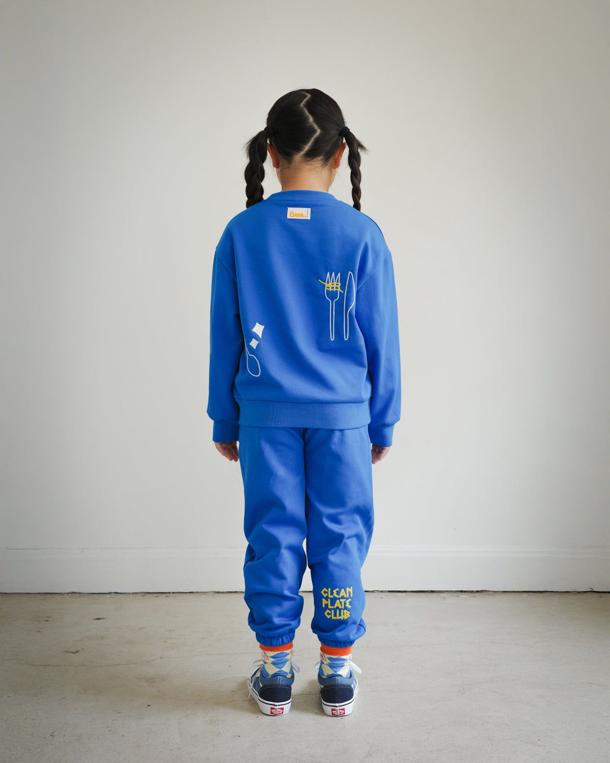 Full outfit back view of kids blue Clean Plate Club sweatshirt styled with matching embroidered sweatpants from Brrr. The sweatshirt features playful food-themed chain embroidery, including a plate motif on the front and fork and knife design on the back, combining comfort, style, and durability for everyday wear.