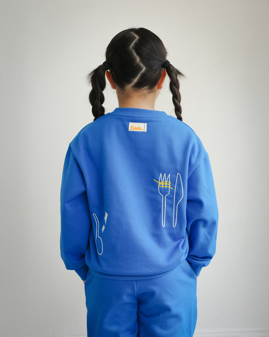Back view of Brrr Clean Plate Club kids sweatshirt in blue, featuring chain-stitched embroidery of a fork and knife motif along the back for a fun food-inspired design. Includes medium-weight cotton blend fabric and relaxed fit, perfect for cool weather kidswear.