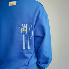 Back view of Brrr kids blue sweatshirt from the Clean Plate Club collection, featuring chain-stitched embroidery of a fork and knife with playful yellow spaghetti detail. The sweatshirt also includes the signature Brrr main label stitched at the back neckline, designed in a cotton-polyester blend for comfort and durability in children’s fashion.