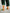 Back view of kids color block socks with four-tone knit design in yellow, orange, green, and burgundy, with Brrr face logo detail on the ankle, paired with rolled-up green overalls