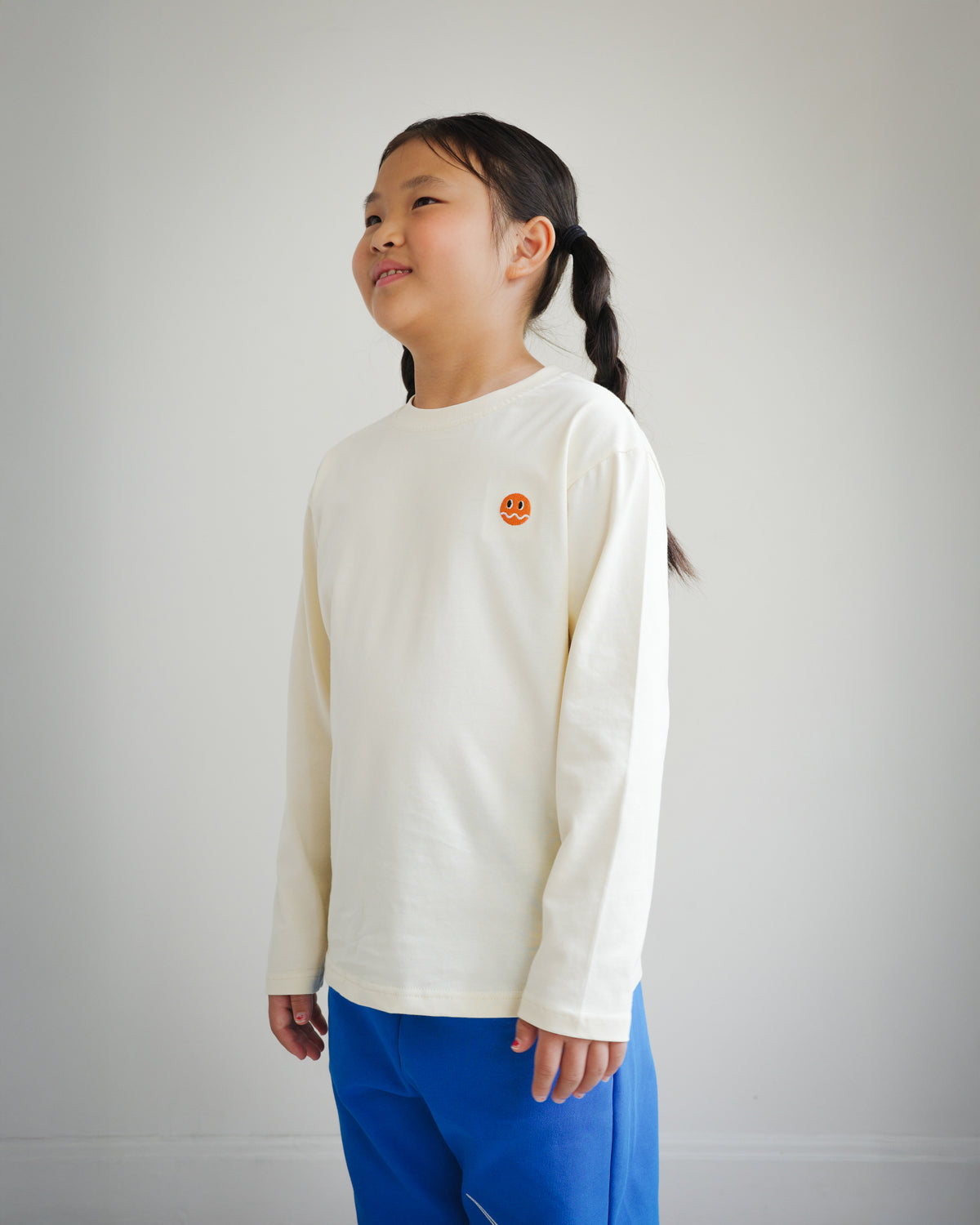 Side view of children’s ivory long sleeve shirt featuring embroidered Brrr logo detail