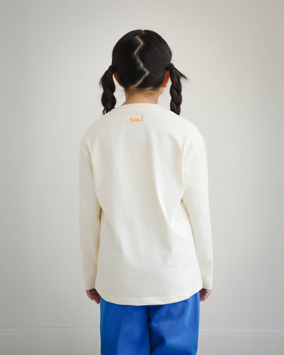 Back view of kids ivory cotton long sleeve t-shirt with Brrr main label on the outside back neck