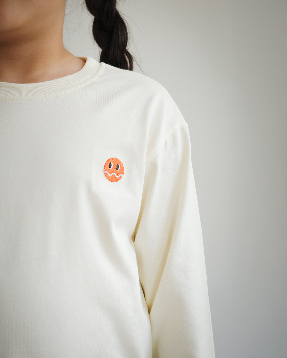 Close-up of embroidered Brrr logo on kids ivory cotton t-shirt