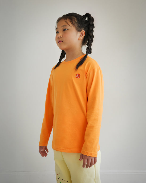 Side view of children’s orange long sleeve shirt with embroidered Brrr logo on chest