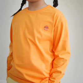 Close-up of embroidered Brrr logo on kids orange cotton t-shirt