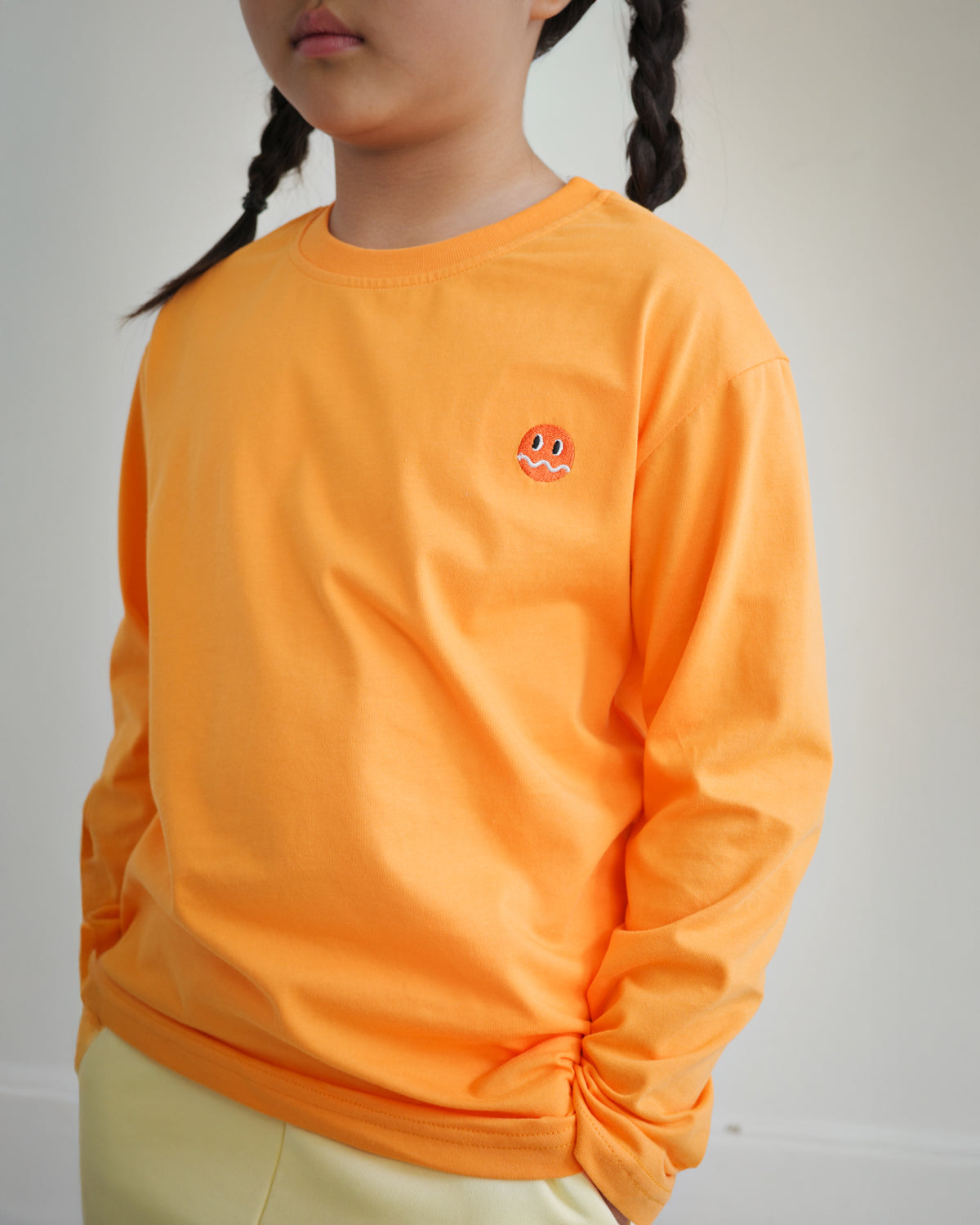 Close-up of embroidered Brrr logo on kids orange cotton t-shirt