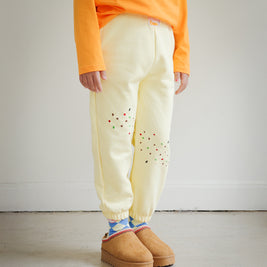 Side view of Brrr kids yellow sweatpants with cookie crumb and ant chain embroidery on the front thigh. Designed for durability and comfort, combining playful food-inspired details with a casual oversized kidswear fit.