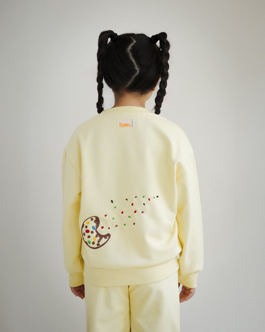 Back view of kids yellow sweatshirt by Brrr, featuring additional cookie crumb and ant chain embroidery along with playful food-inspired details. The sweatshirt combines comfort with whimsical design, reflecting the Sweet Tooth Club theme.